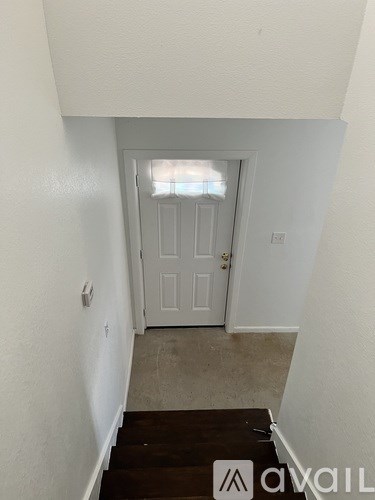 A hallway with a white door and a window above it.