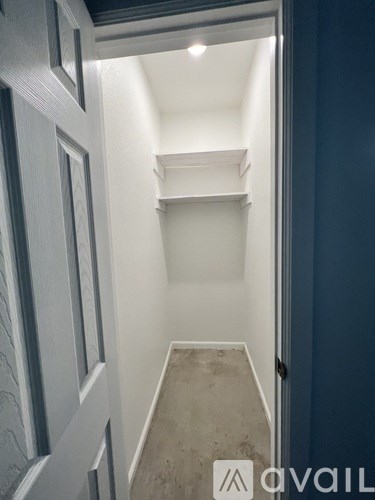 A small, empty room with a door on the left and a wall on the right.
