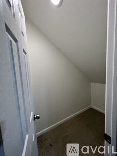 A white door with a silver handle is in a room with white walls and a brown floor.