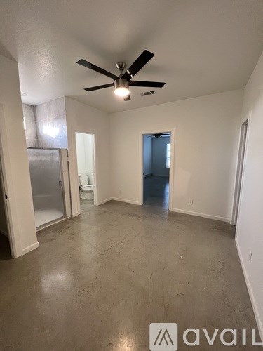 A room with a ceiling fan and a door leading to a bathroom.