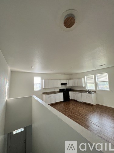 A white kitchen with wooden floors and white cabinets.