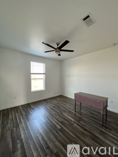 A room with a ceiling fan and a table with a window.