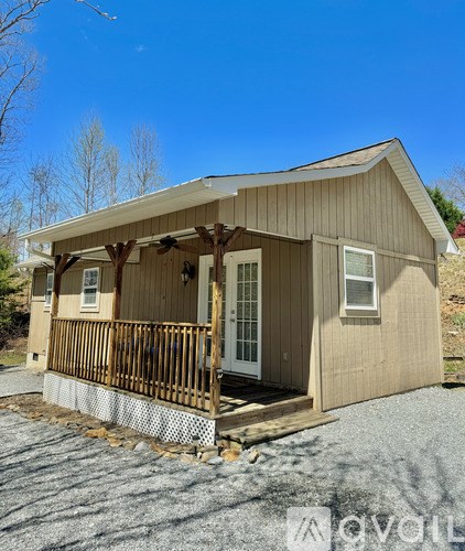 A small wooden house with a porch and a covered entrance.