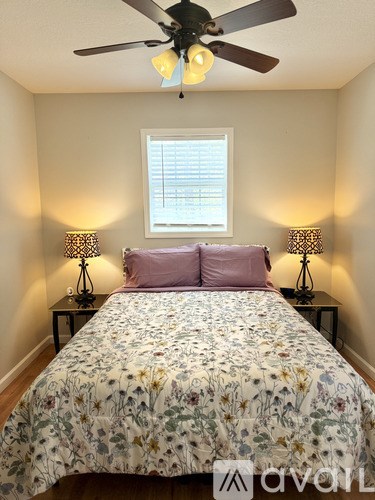 A bedroom with a floral bedspread and two lamps on either side of the bed.