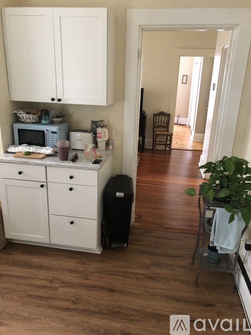 A kitchen with white cabinets and a wooden floor.