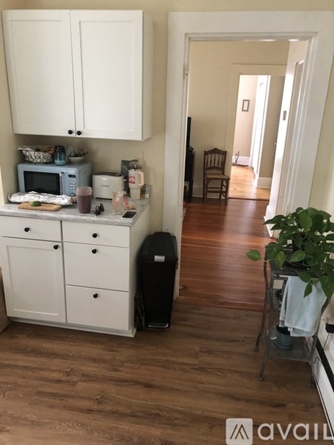A kitchen with white cabinets and a wooden floor.
