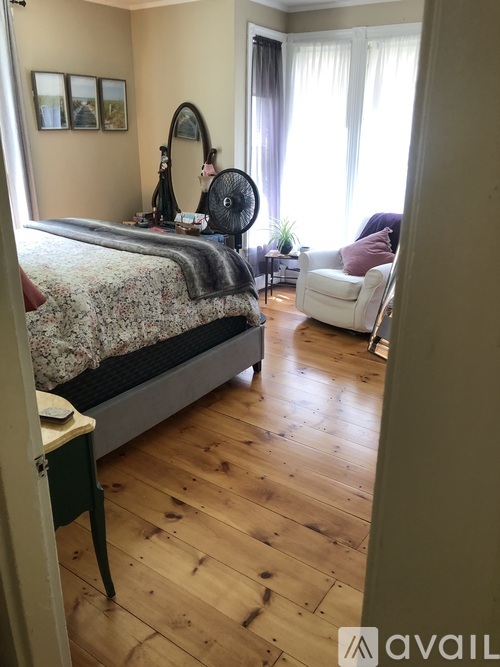 A bedroom with a large bed and a chair.