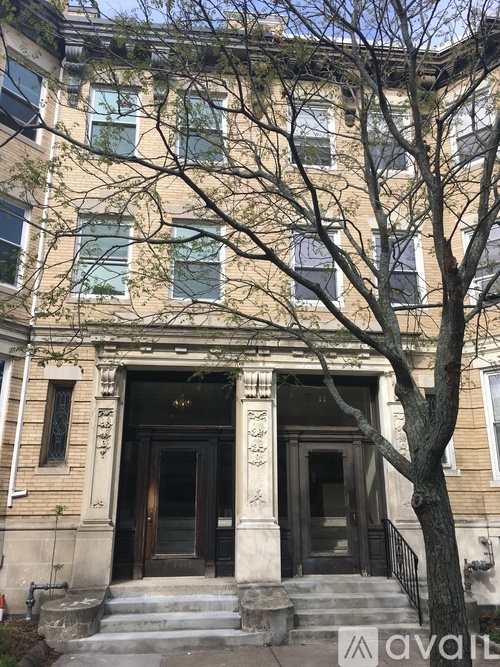 A large tree is in front of a building with a large front door.