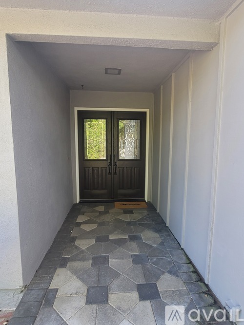 A hallway with a tiled floor and a doorway leading to a balcony.