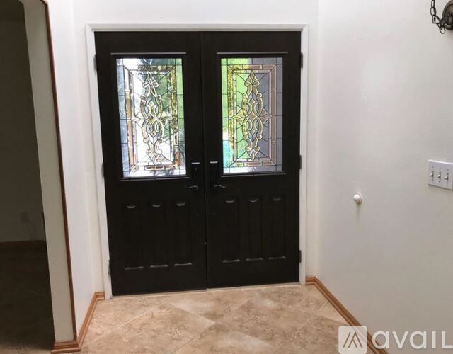A black double door with stained glass panels is in a room with a tiled floor.