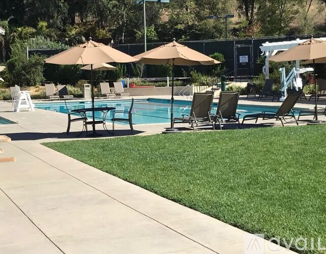 A pool surrounded by lawn chairs and umbrellas.