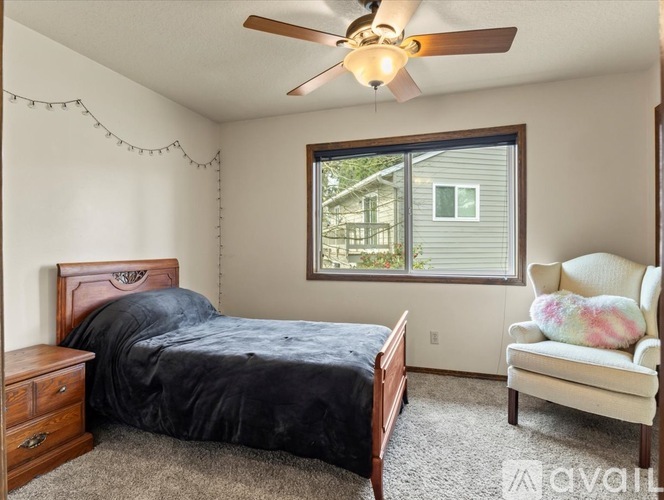 A bedroom with a bed, a chair, and a ceiling fan.