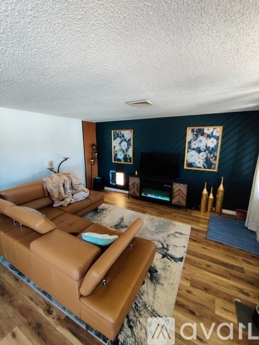 A living room with a brown leather couch and a rug.