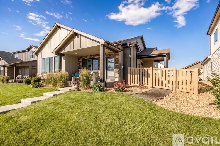 A modern house with a large front yard and a wooden fence.