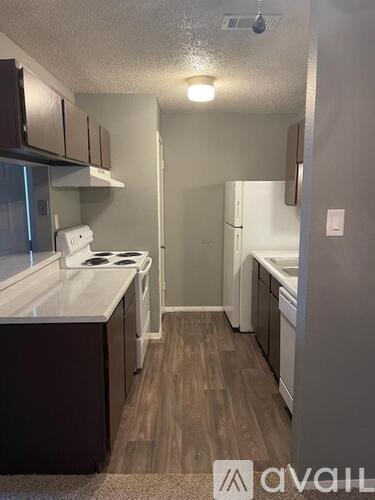 A small kitchen with a white stove top oven and dark brown cabinets.
