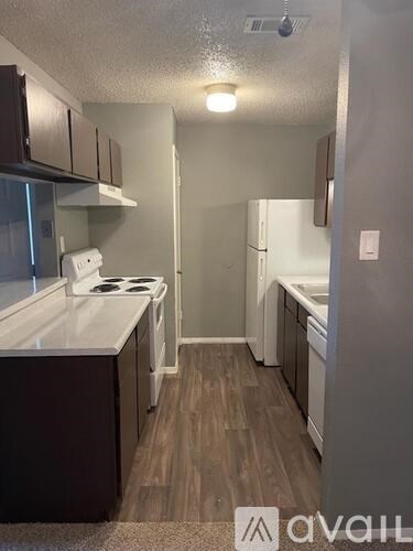A small kitchen with a white stove top oven and dark brown cabinets.