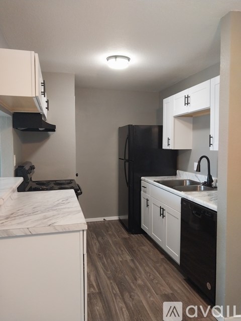 A kitchen with black appliances and white cabinets.