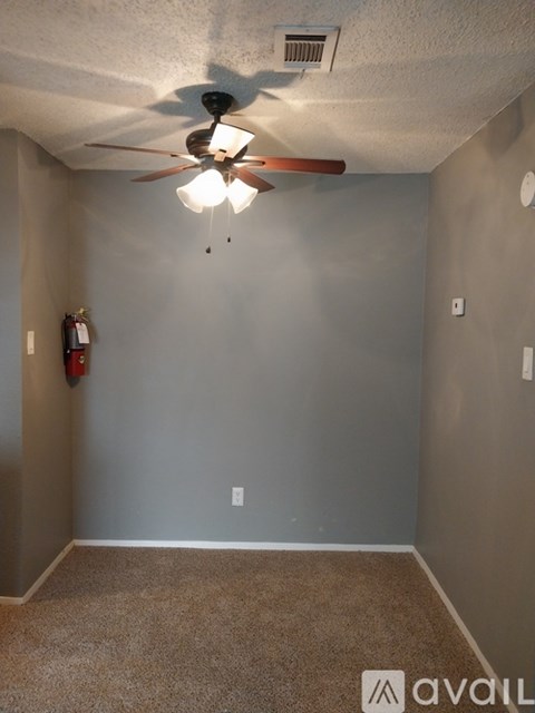 A room with a ceiling fan and a fire extinguisher on the wall.
