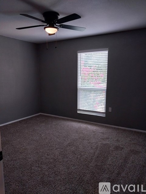 A room with a ceiling fan and a window with blinds.