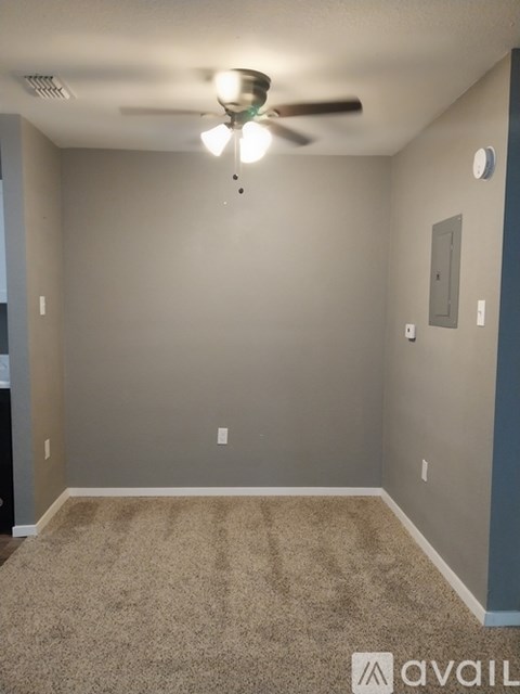 A room with a ceiling fan and carpeted floor.