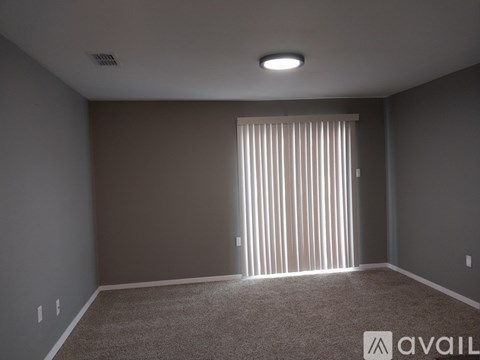 A room with a carpeted floor and a window with blinds.