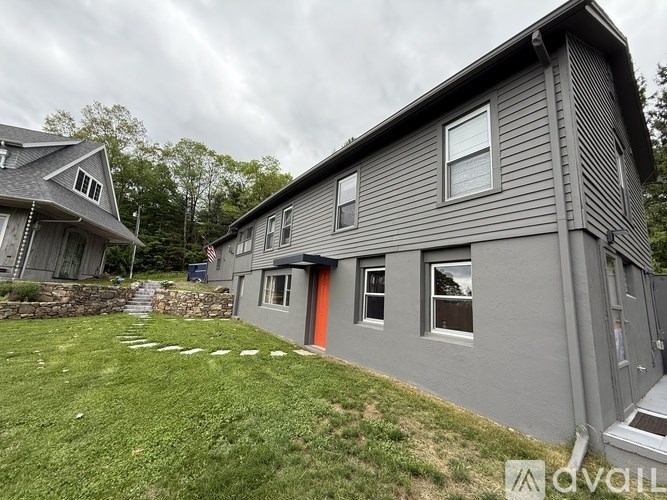 A grey house with a red door is for sale.