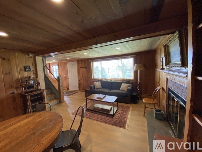 A living room with a couch, a chair, a table, and a fireplace.