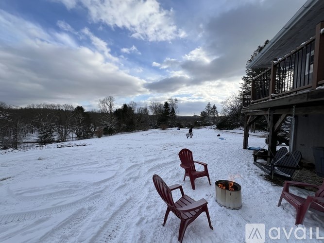 A snowy landscape with a fire pit and chairs.