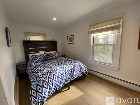 A bedroom with a bed, nightstand, and window.
