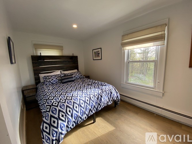 A bedroom with a bed, nightstand, and window.
