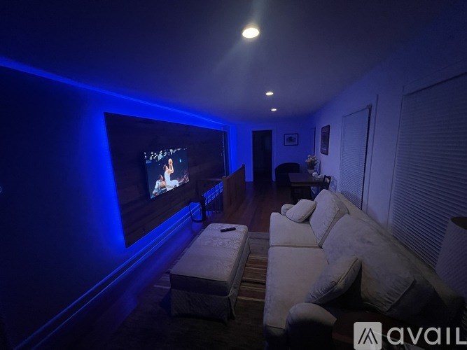 A room with a television on the wall and a couch in front of it.