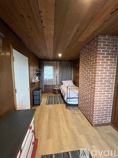 A room with a brick pillar and a bed.