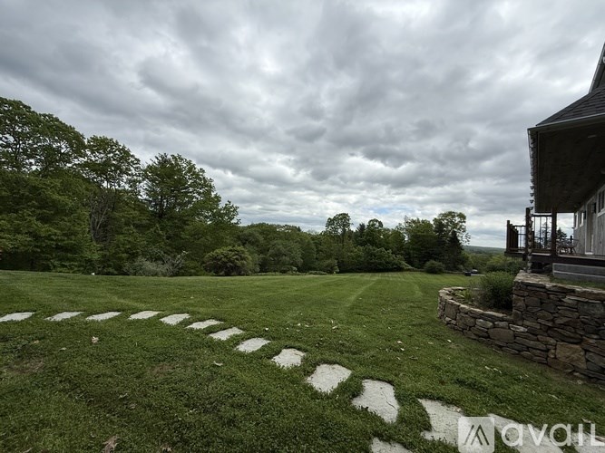 A stone pathway leads to a house in a grassy field.