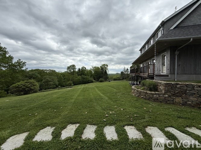 A house with a stone wall and a green lawn in front.