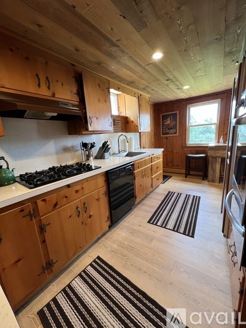 A kitchen with wooden cabinets and a black and white striped rug on the floor.