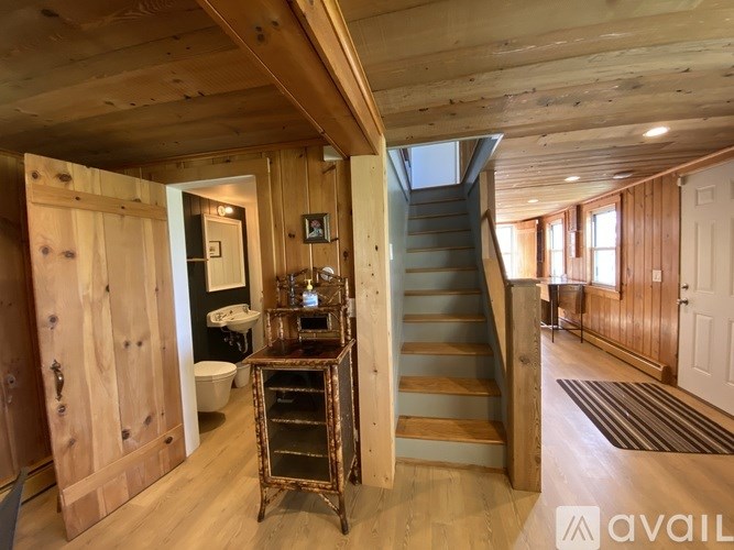 A wooden staircase leads up to a bathroom with a toilet and sink.