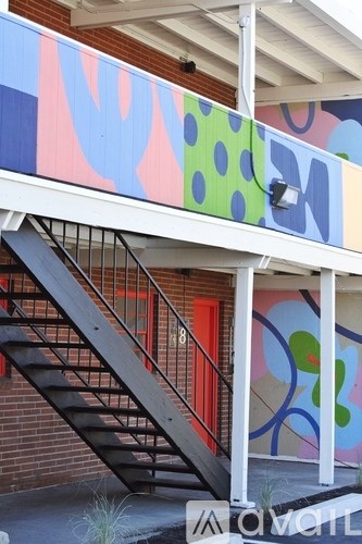 A staircase with a metal railing is in front of a colorful mural.