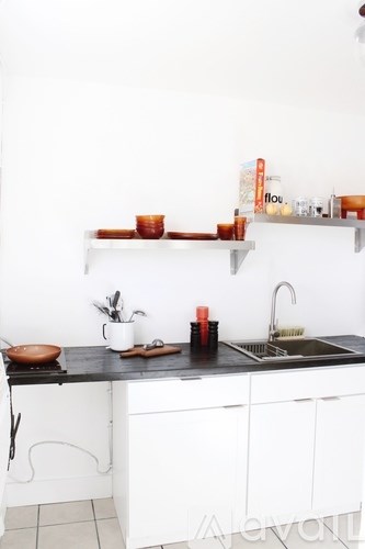 A kitchen with white cabinets and a black countertop.