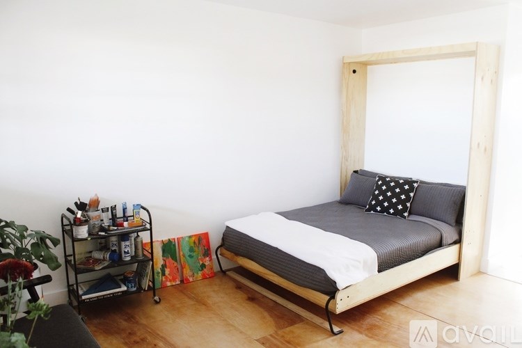 A bedroom with a bed, a cart, and a plant.