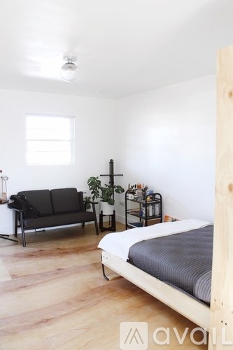 A bedroom with a bed, a sofa, and a table with a plant on it.