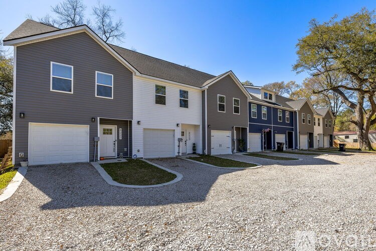 A modern two-story house with a gravel driveway in front.