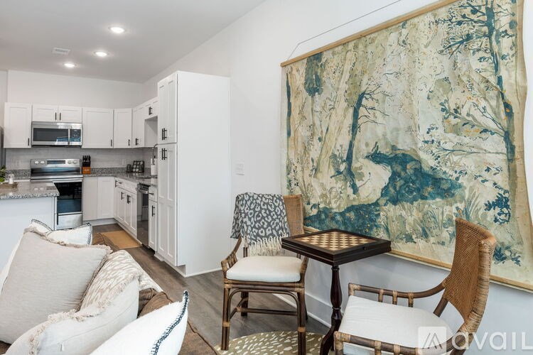 A living room with a large painting on the wall and a dining area with a table and chairs.