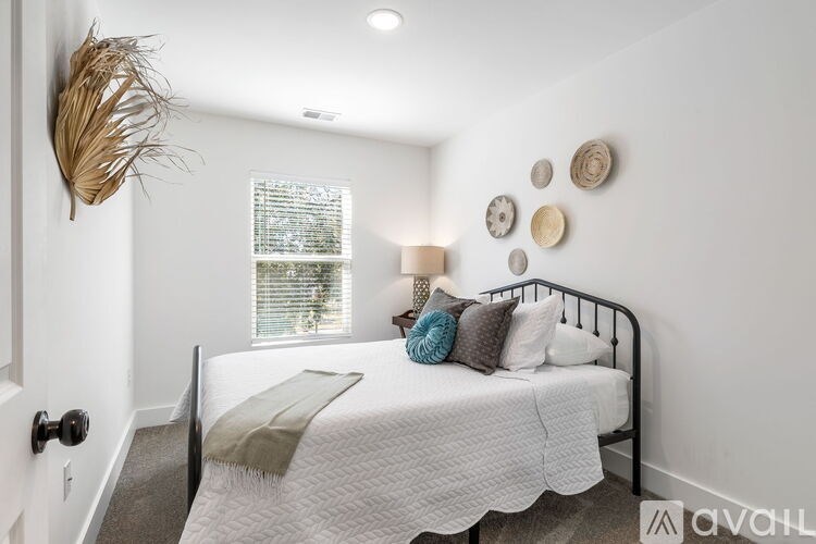 A bedroom with a bed, a lamp, and a wall decoration.