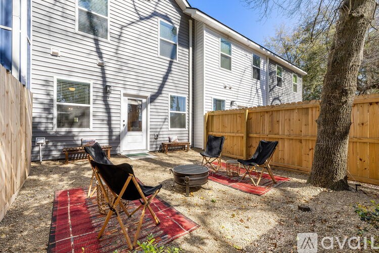A backyard with a red rug and two chairs.