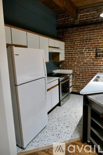 A kitchen with a white fridge and a brick wall.