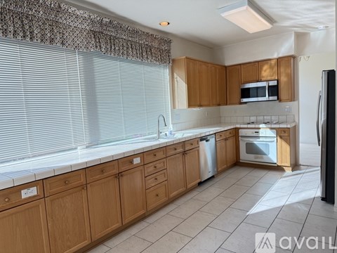 A kitchen with wooden cabinets and a black refrigerator.