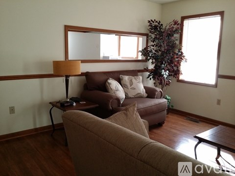 A living room with a brown couch and a plant on the windowsill.