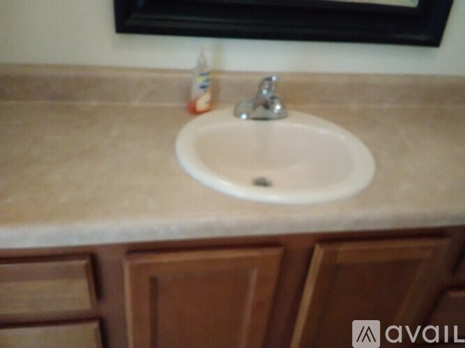 A bathroom sink with a brown cabinet below it.
