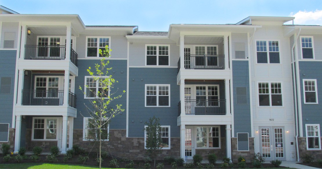 an apartment building with a green yard in front of it