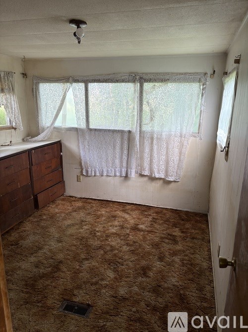 A room with a carpeted floor and a window with curtains.
